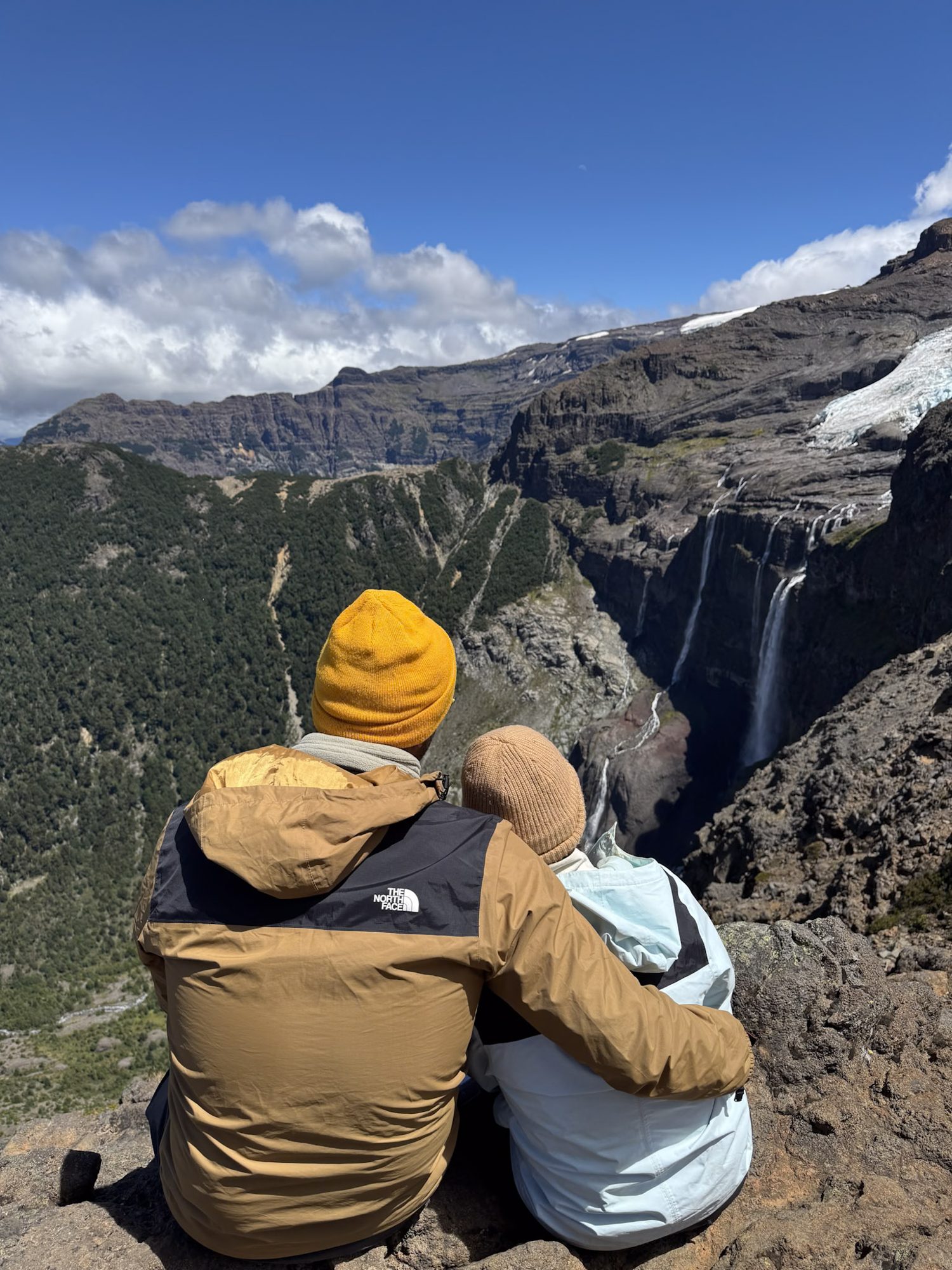 Casal abraçado de costas admirando uma grande cascata e glaciar no Parque Nacional Nahuel Huapi, Bariloche, Patagônia argentina