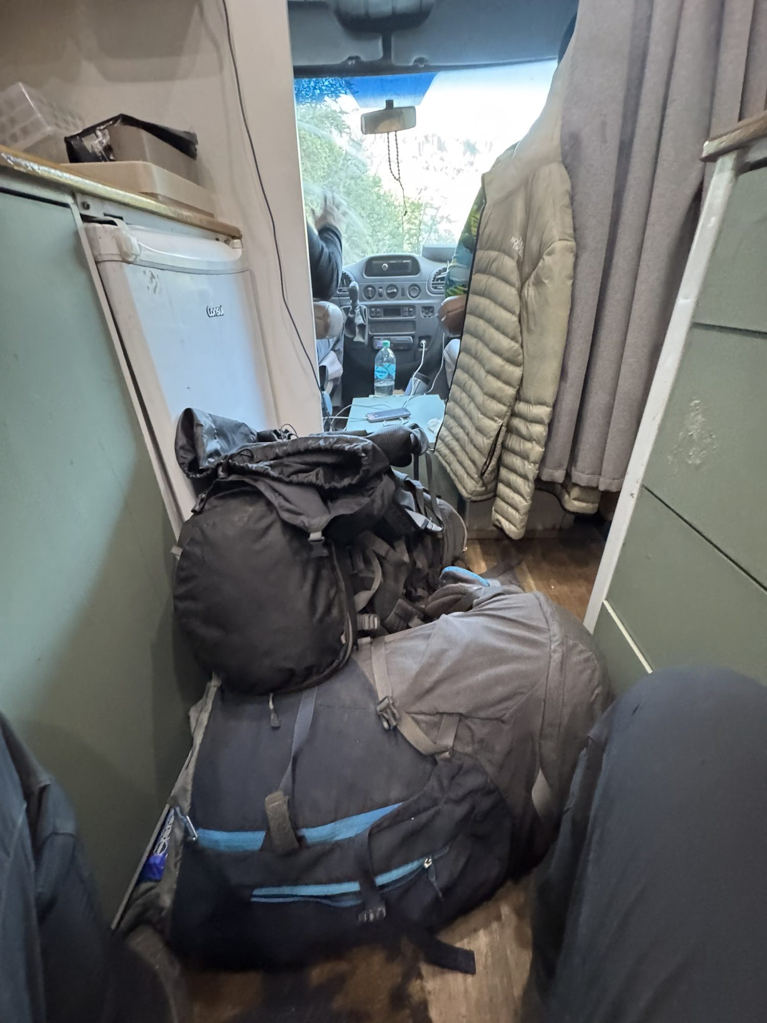 Mochilas grandes de trekking empilhadas no corredor estreito de uma van durante transfer para lá em cima, na Patagônia argentina