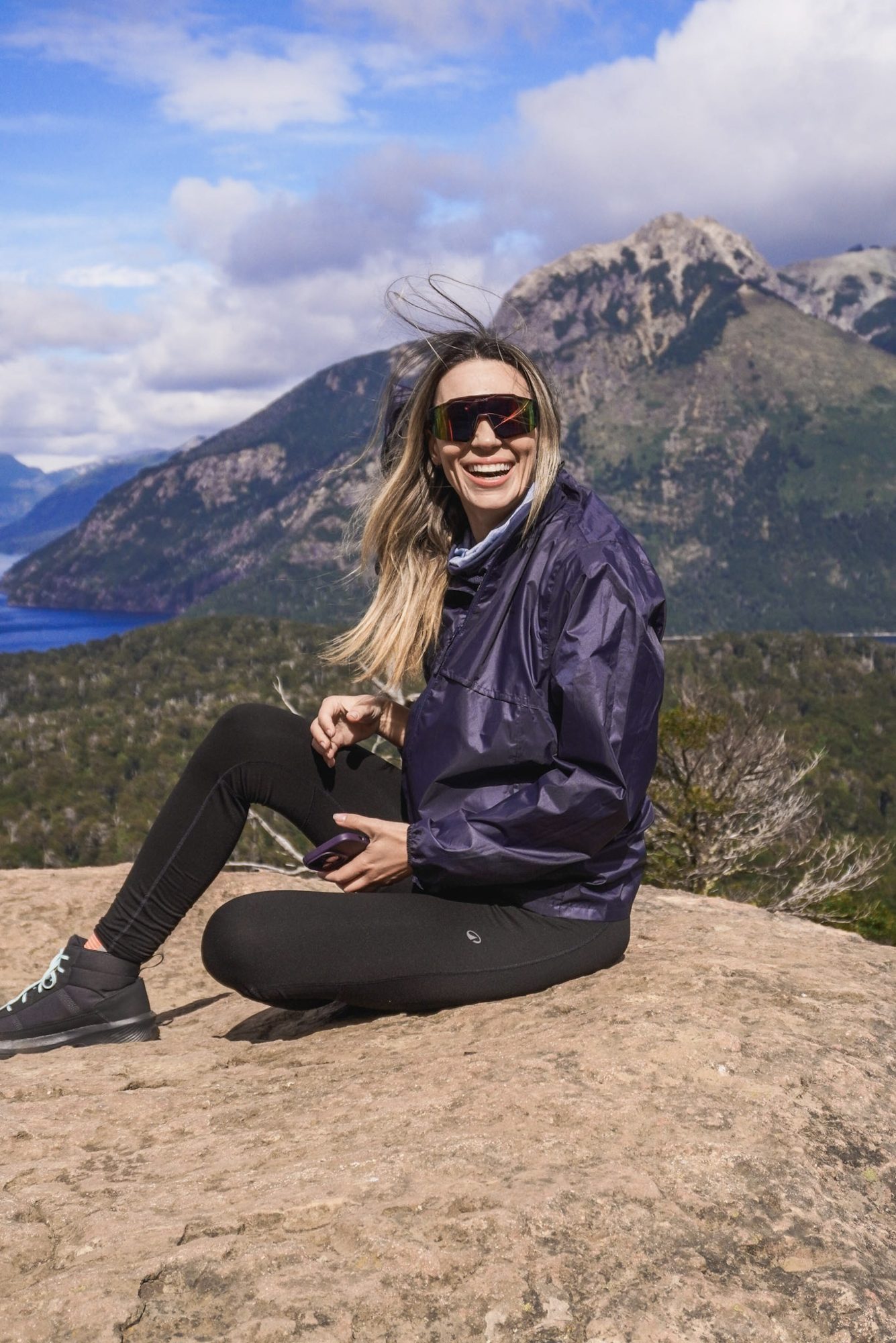 Mulher sentada em rocha com vista para lago e montanhas em Bariloche