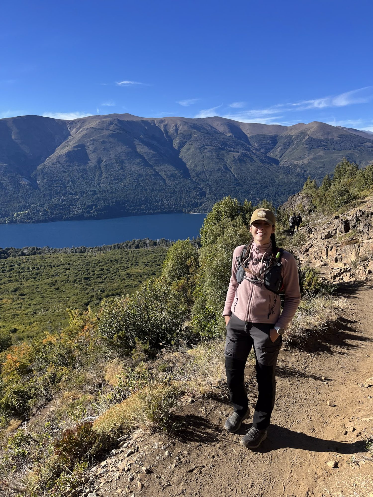 Pessoa em trilha com lago e montanhas ao fundo em Bariloche