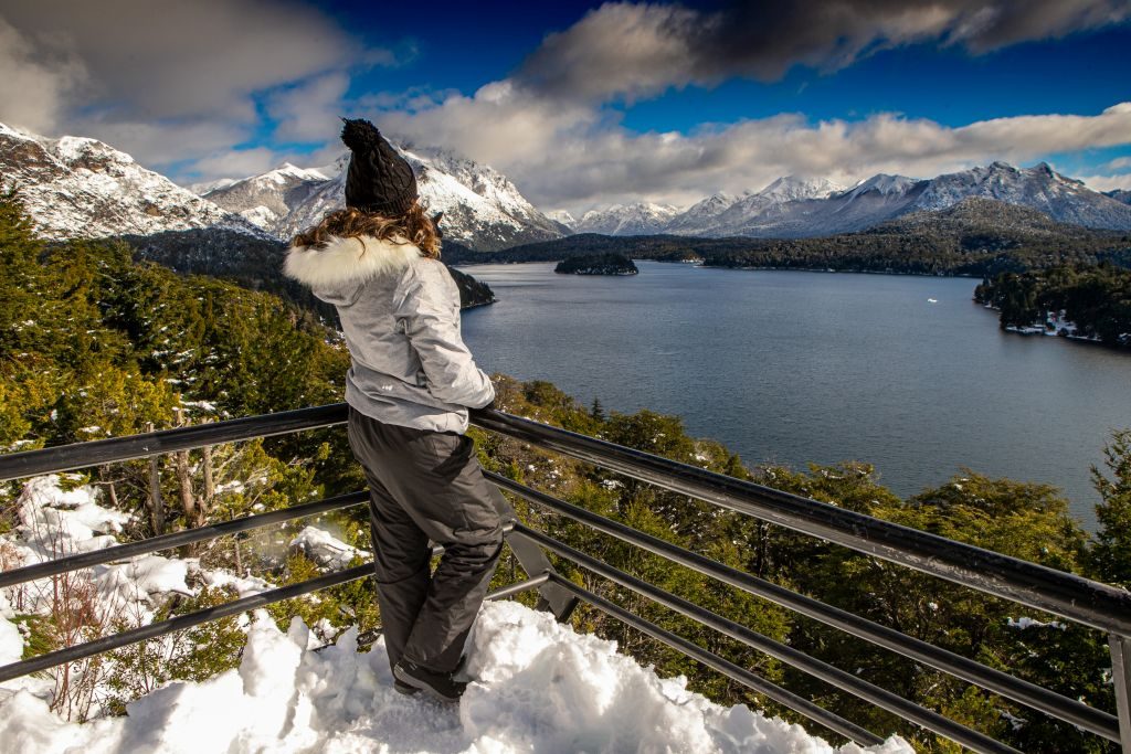 Vista do alto de montanha rochosa com névoa de neve e lago ao fundo em Bariloche