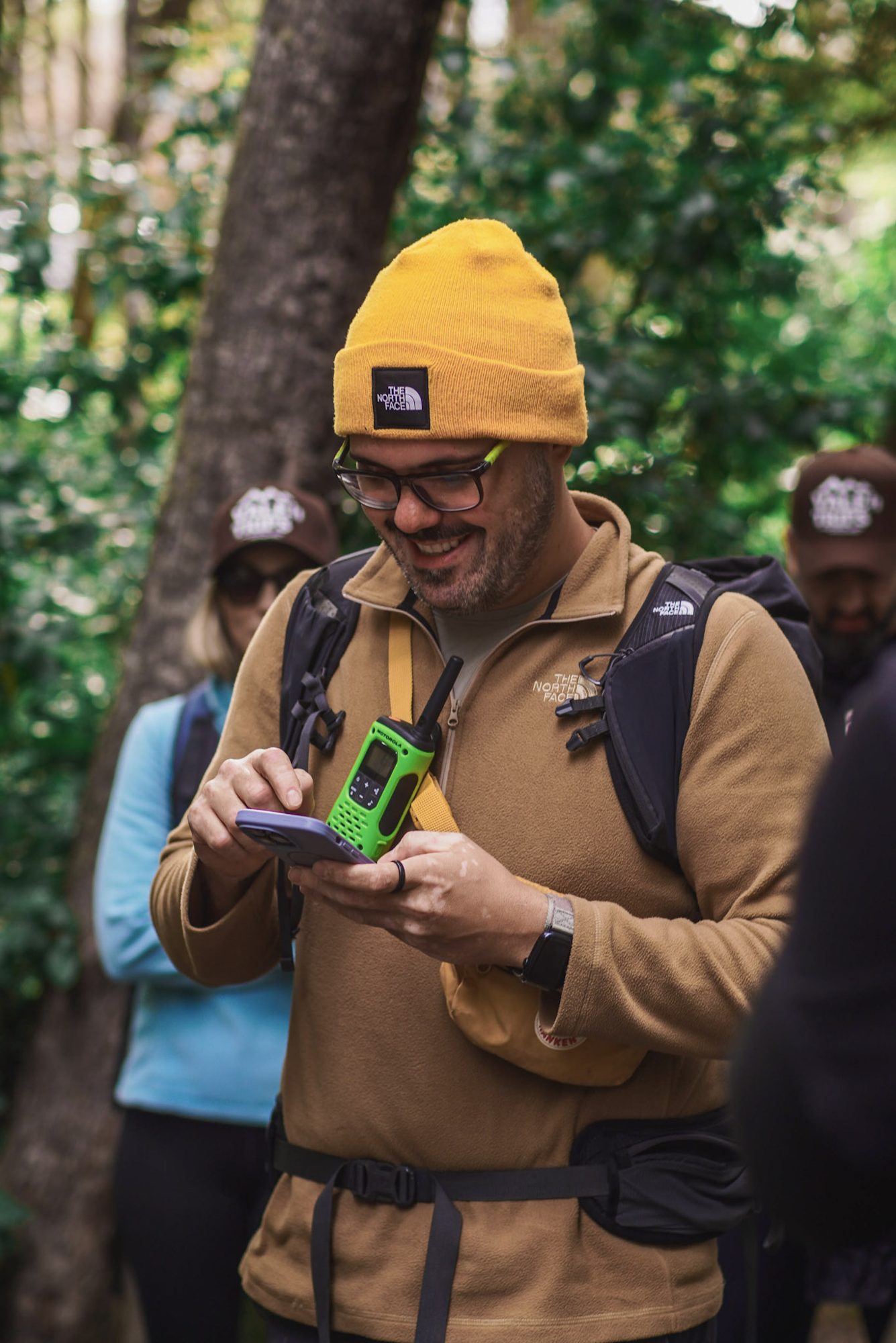 Guia de trekking com touca The North Face e rádio comunicador na floresta patagônica durante trilha em grupo