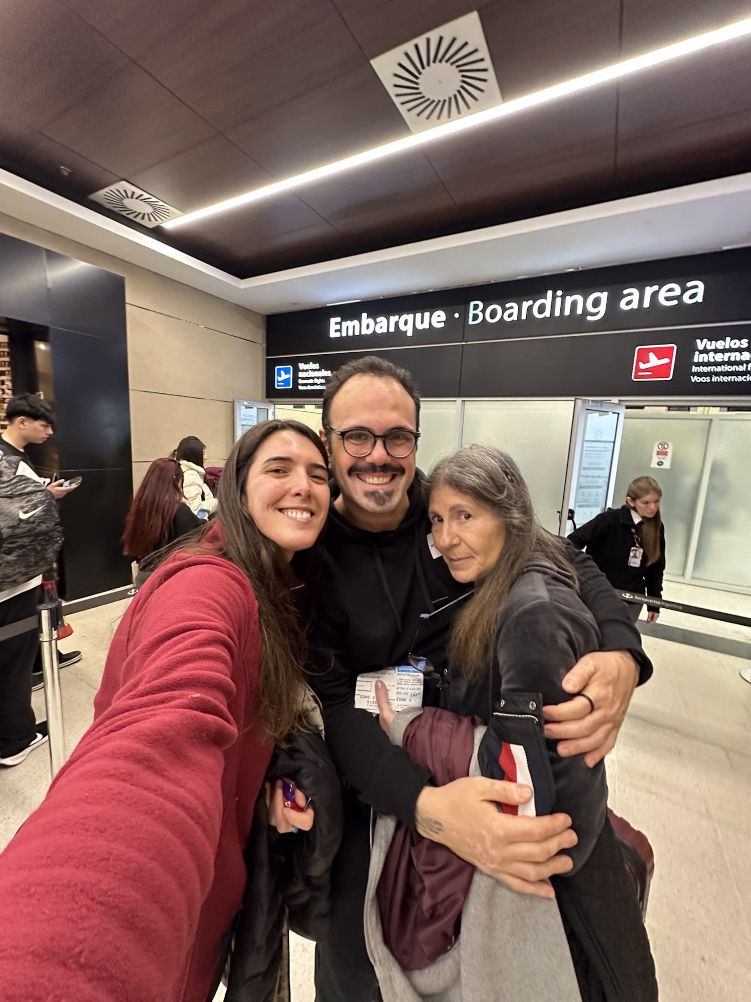 três amigos posam juntos para selfie na área de embarque do aeroporto de Bariloche - Vale Liberdade