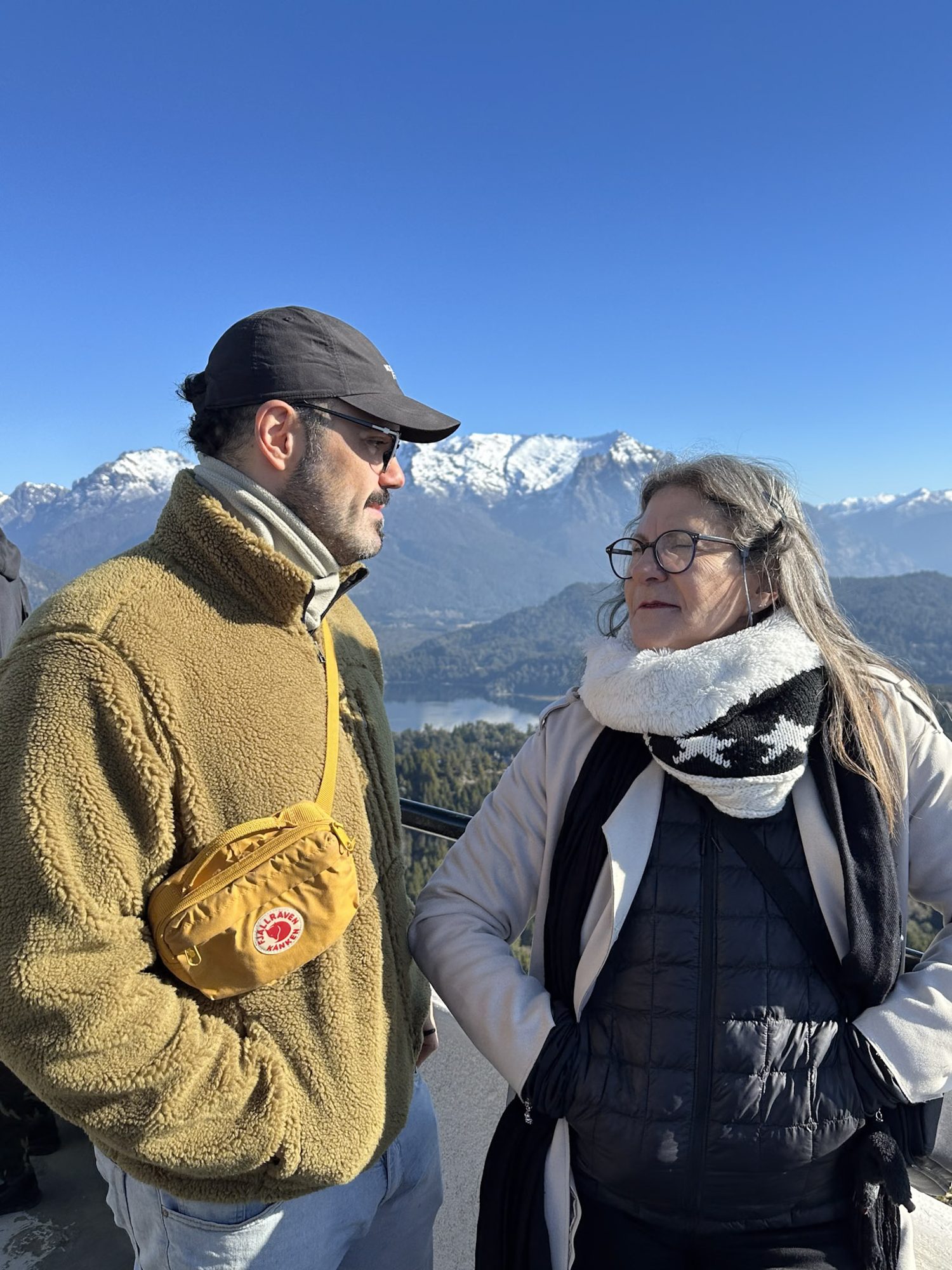 Bariloche em julho: duas pessoas conversam com vista para montanhas nevadas em Bariloche - Vale Liberdade