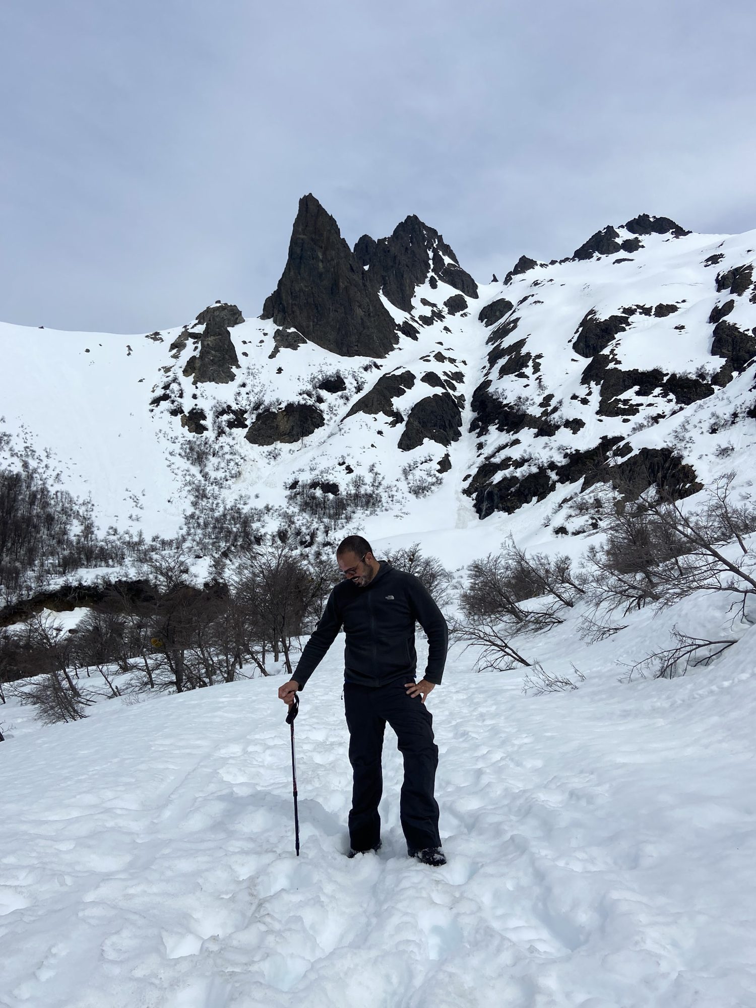 Bariloche em Outubro: Caminhante com bastão posando na neve com picos rochosos ao fundo em Bariloche - Vale Liberdade