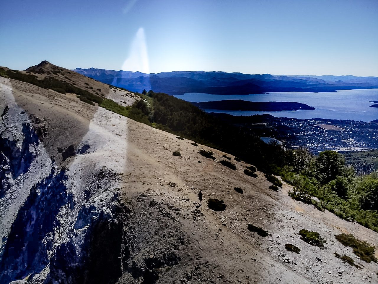 onde fica bariloche: Vista do alto de morro rochoso com cidade e lago azul ao fundo em Bariloche - Vale Liberdade