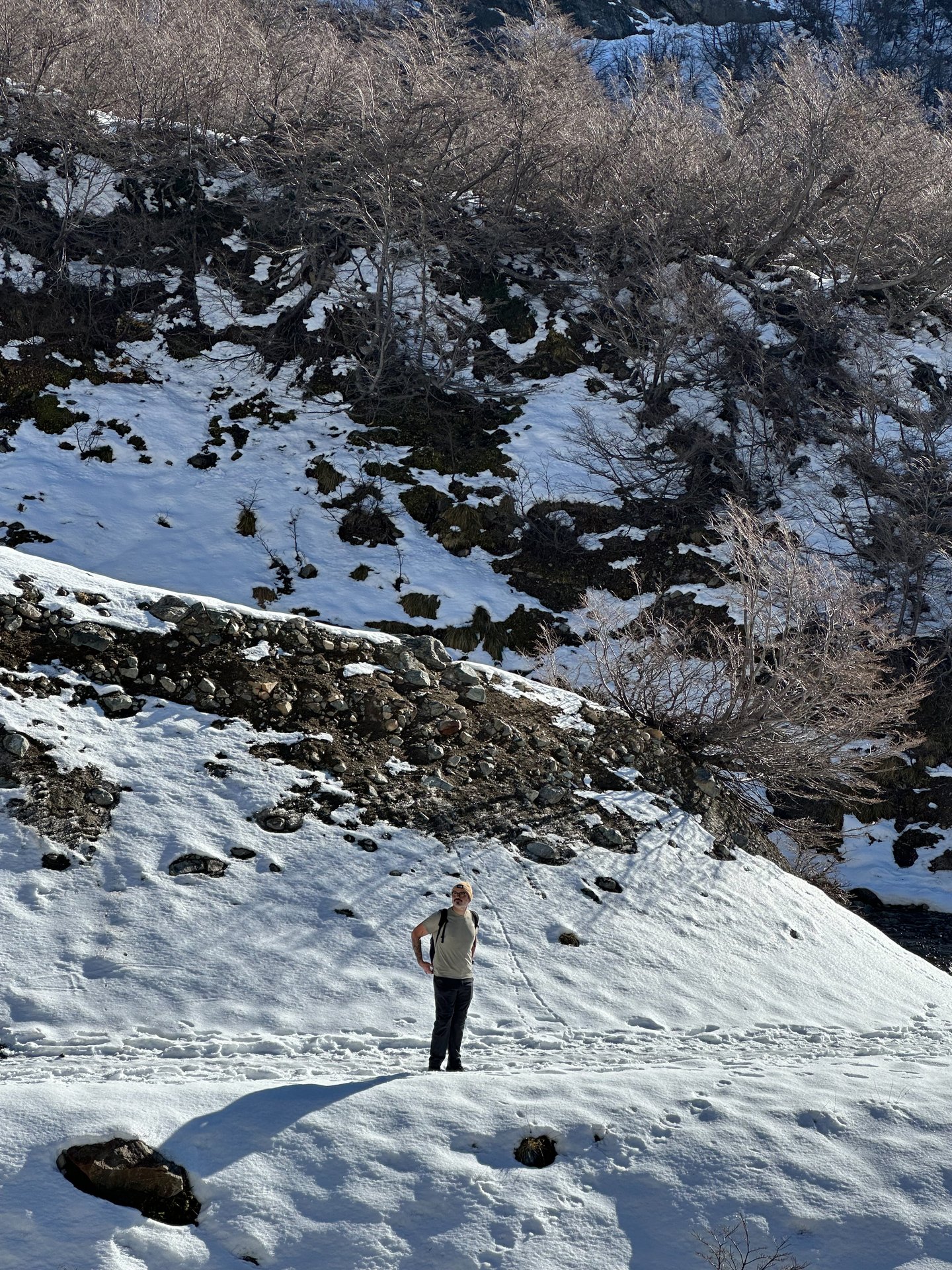 Pessoa em encosta nevada do Refúgio López com vale ao fundo, ilustrando o trecho final com neve.
