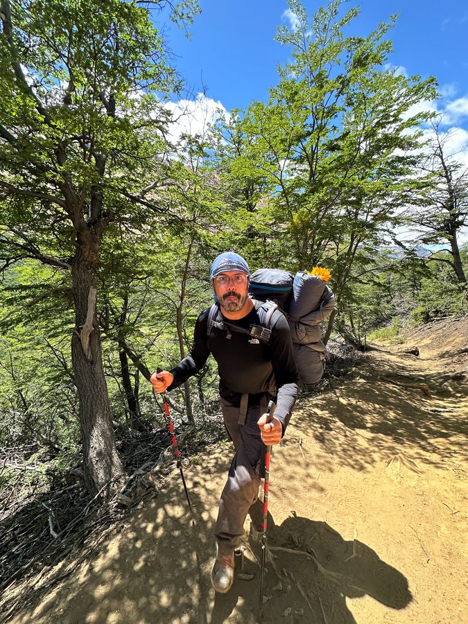 Homem com mochila e bastões de trekking em trilha no Refúgio Frey