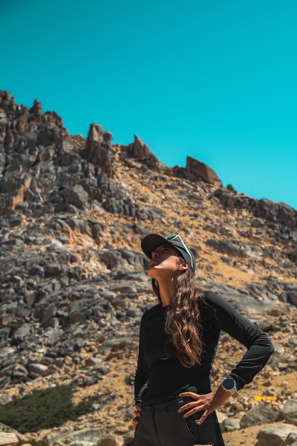 Mulher em trekking de costas com mochila mostrando equipamento típico