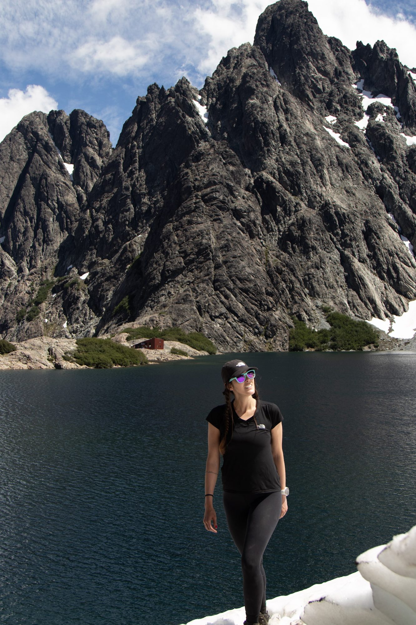 trail running feminino: Mulher posando em frente a lago alpino com paredões rochosos ao fundo no Refúgio Frey - Vale Liberdade