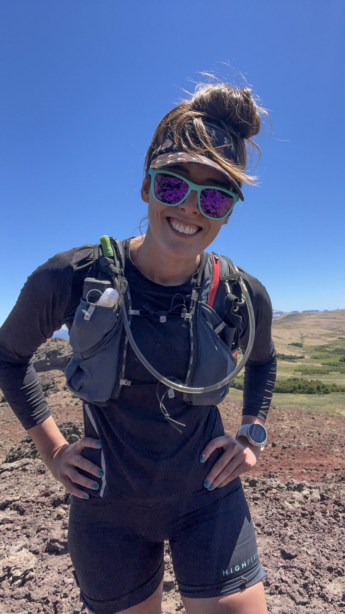 trail running feminino: Mulher sorridente com equipamento de trail running em paisagem árida de montanha - Vale Liberdade