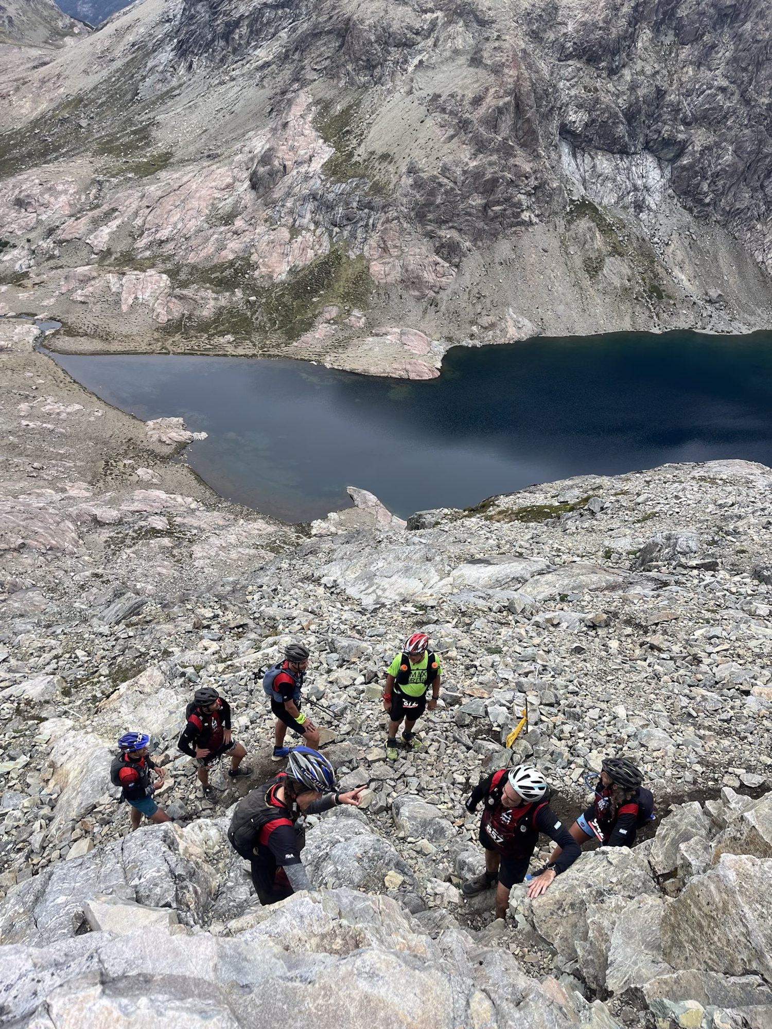 Vulcão Lanín: grupo de alpinistas escalando terreno rochoso com lago glacial ao fundo em Bariloche - Vale Liberdade