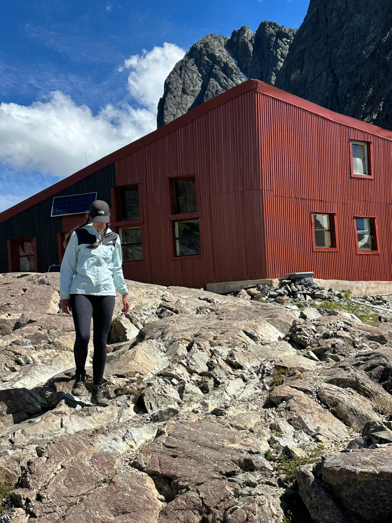 bariloche em janeiro: Mulher em roupa de trekking em frente ao Refúgio Frey no Cerro Catedral, Bariloche, com paredão rochoso ao fundo