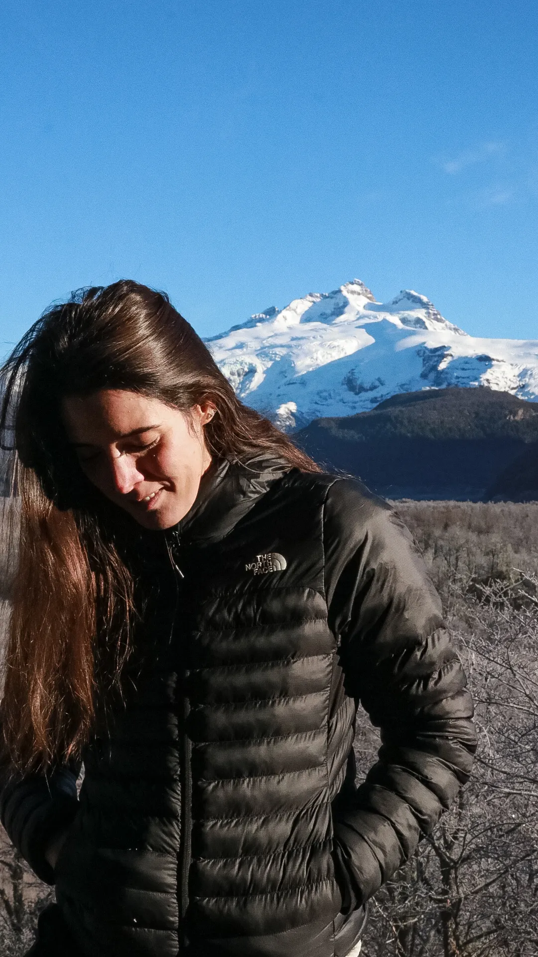 bariloche em maio: Mulher de jaqueta preta The North Face com o cume nevado do Cerro Tronador ao fundo em Bariloche, Patagônia argentina