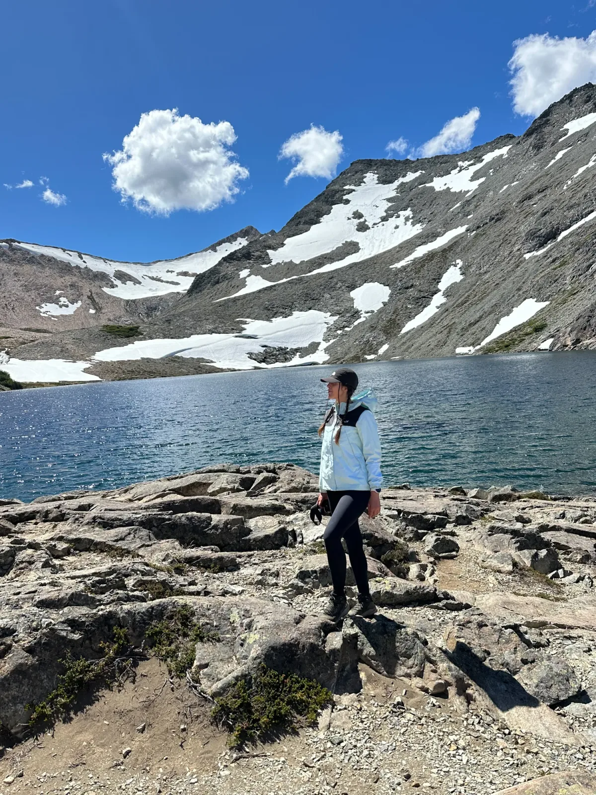 Laguna Negra Bariloche: Mulher em lago glacial de altitude na Patagônia argentina, com montanhas cobertas de neve ao fundo em dia de sol