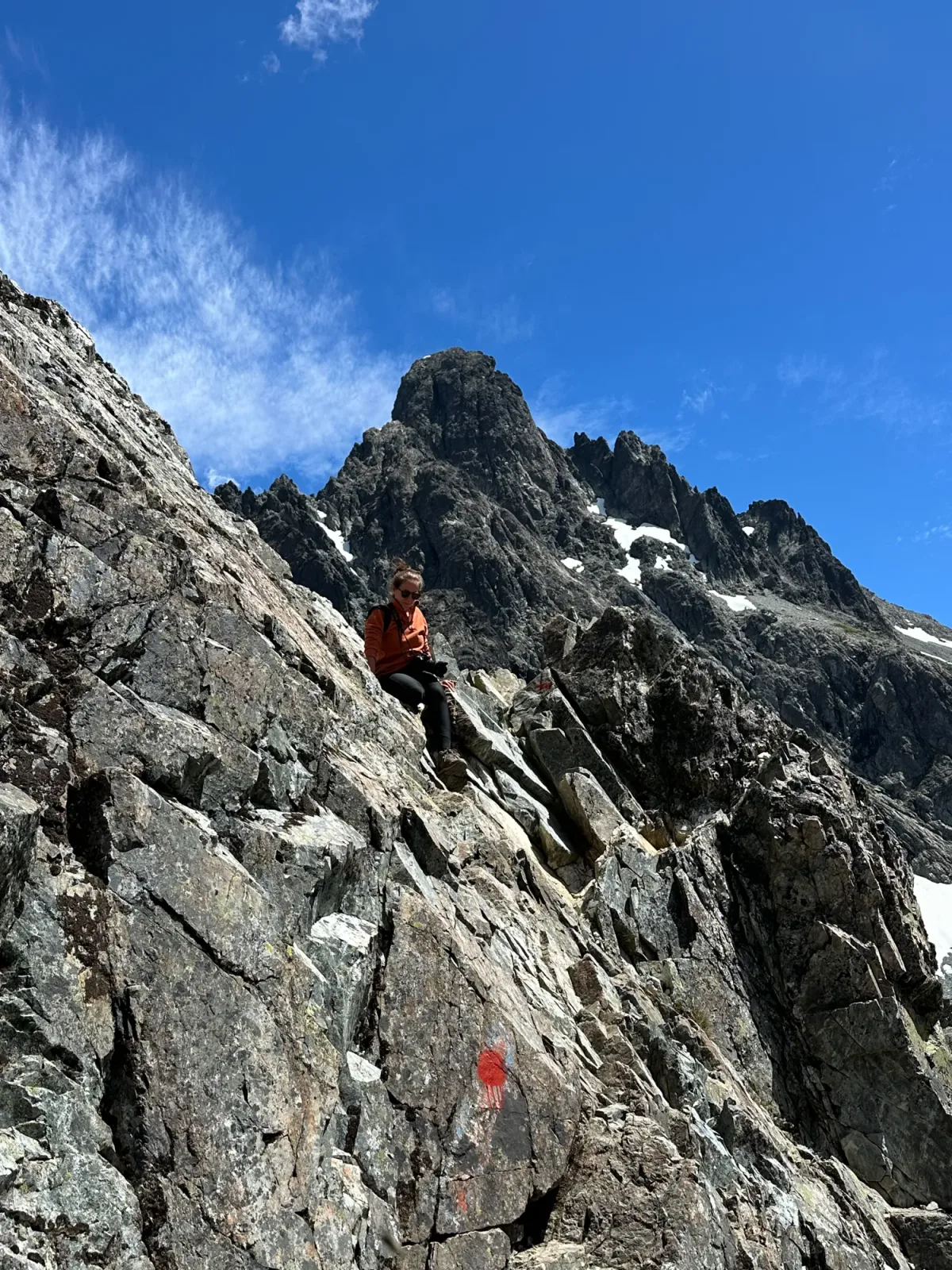 Laguna Negra Bariloche: Trilheiro descansando em trecho rochoso e exposto de trekking na Patagônia argentina, com picos graníticos e neve ao fundo em Bariloche