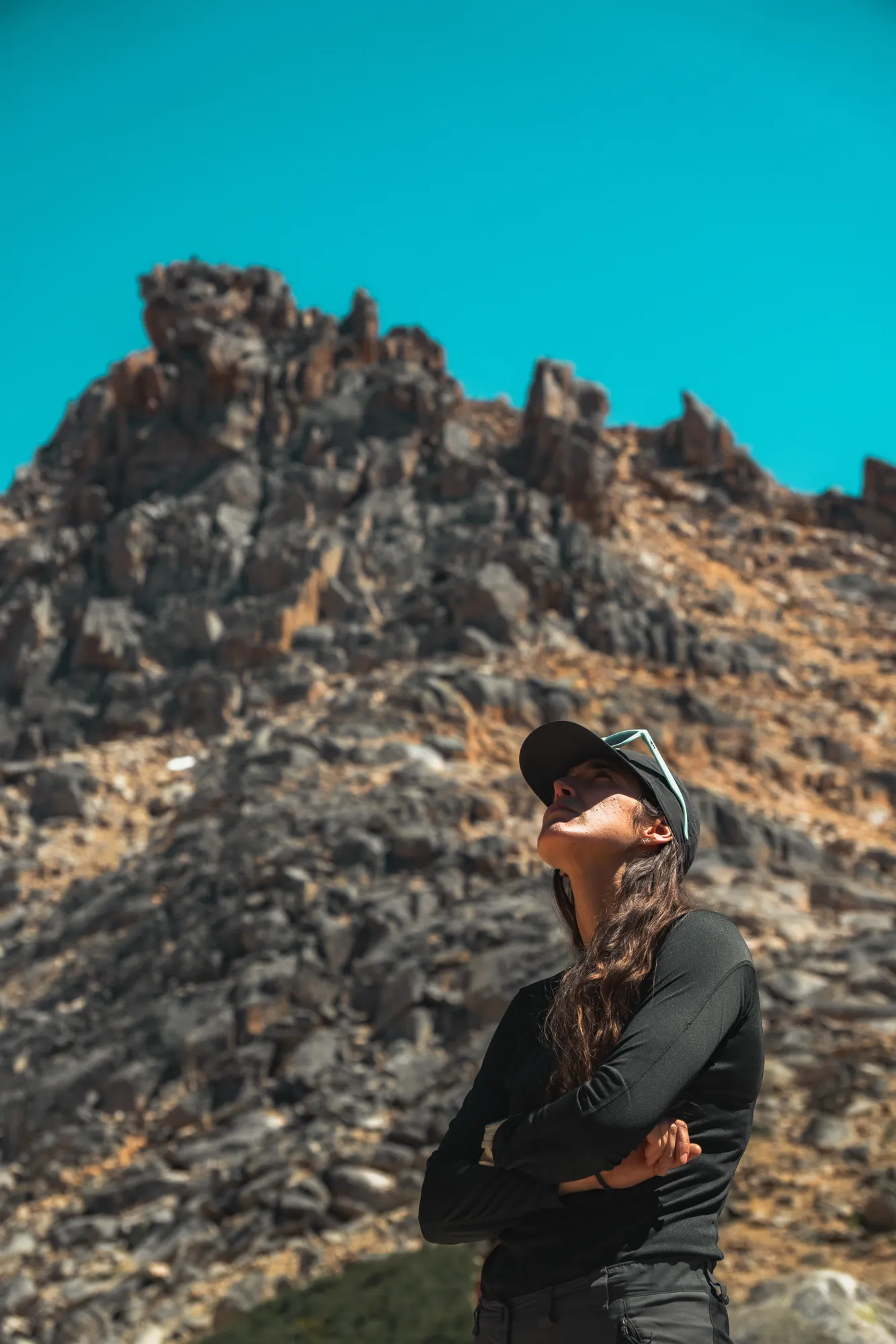 o que é trekking: Mulher em trilha de trekking em Bariloche com paredão rochoso e céu azul na Patagônia argentina