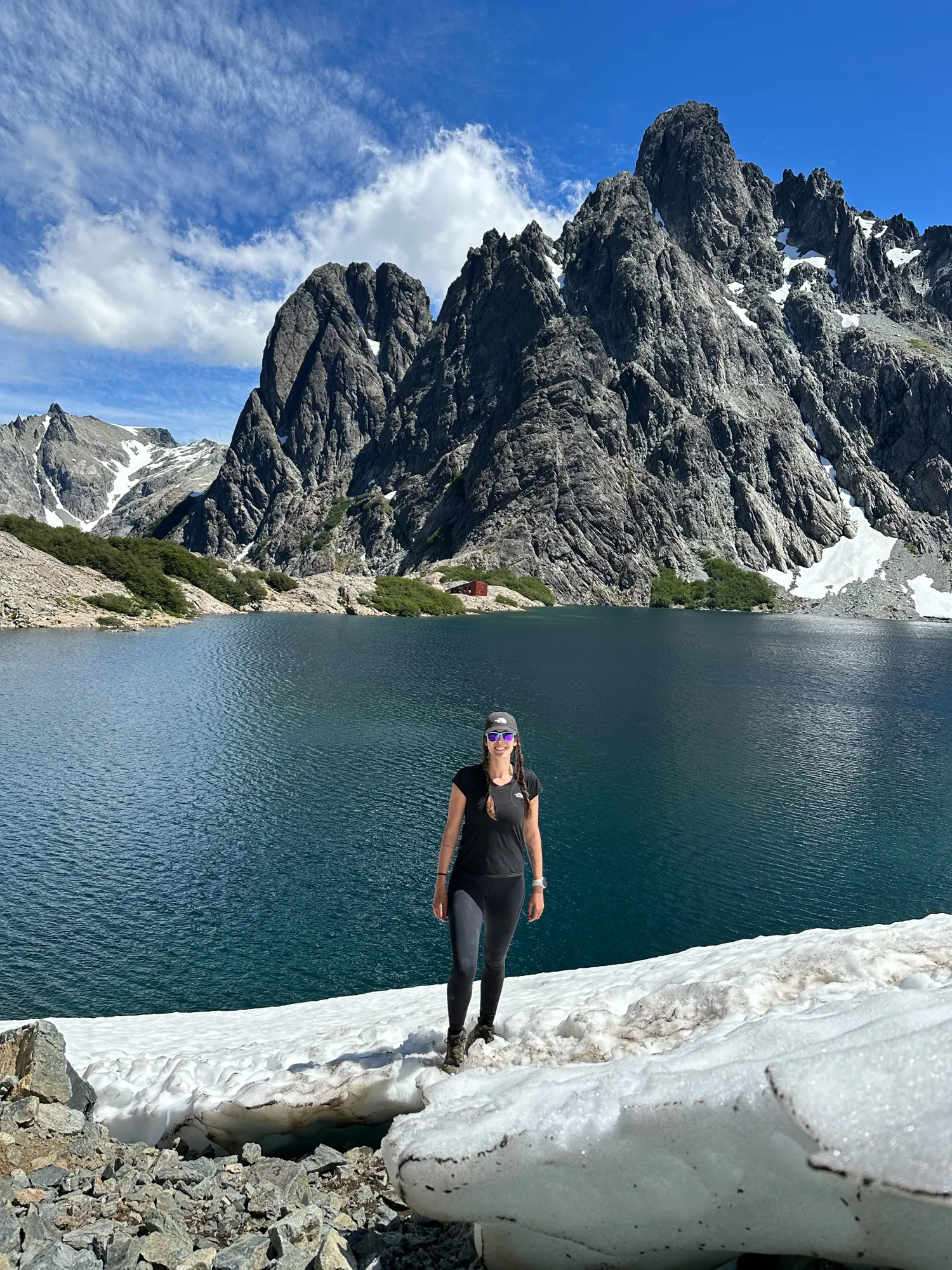 onde se hospedar em bariloche: Mulher em pé sobre neve à beira da Laguna Negra com picos rochosos do Cerro Catedral ao fundo, em Bariloche, Patagônia argentina