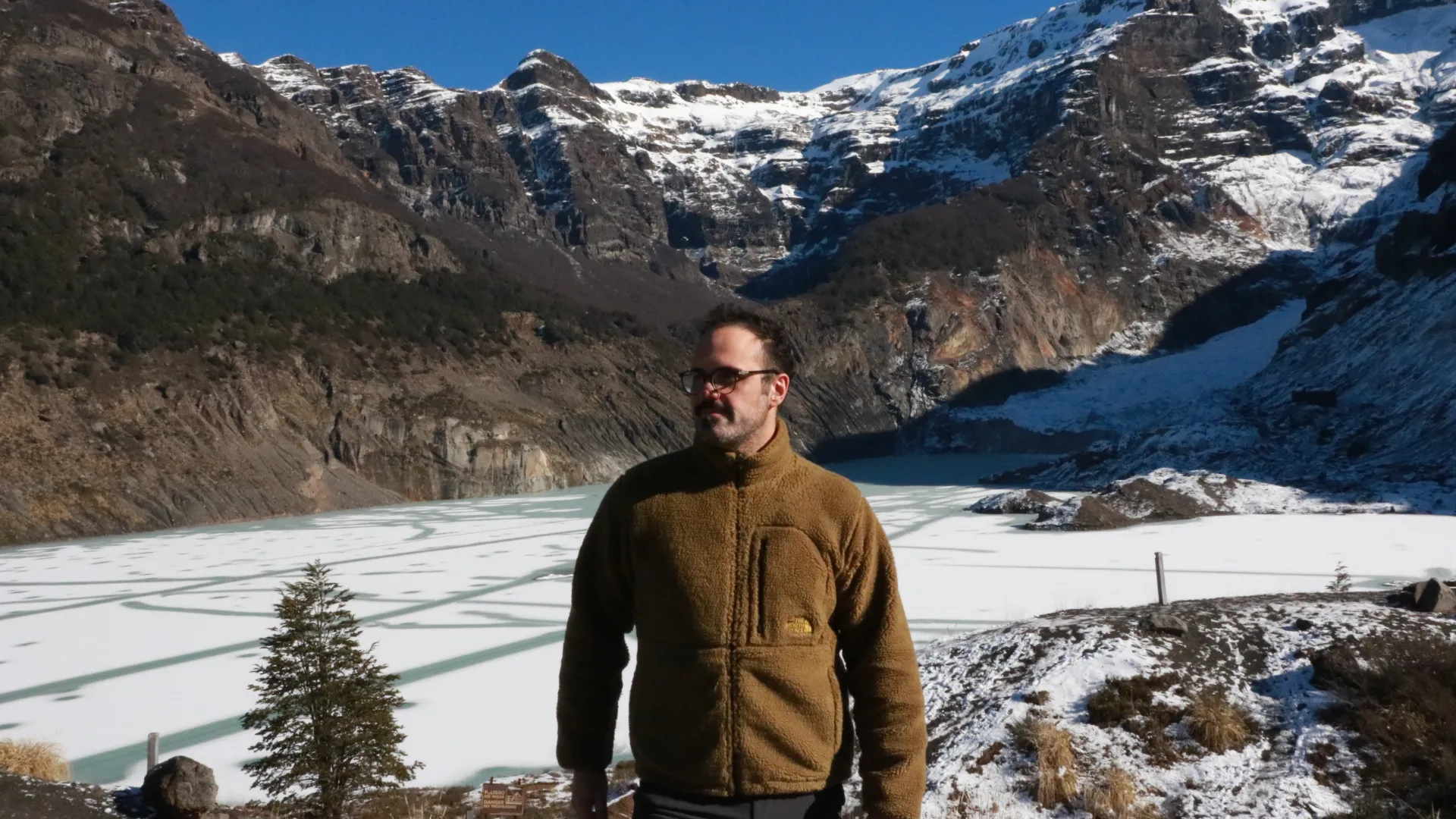 patagonia run: Viajante posando diante de lago congelado com montanhas cobertas de neve ao fundo em Bariloche, Patagônia argentina