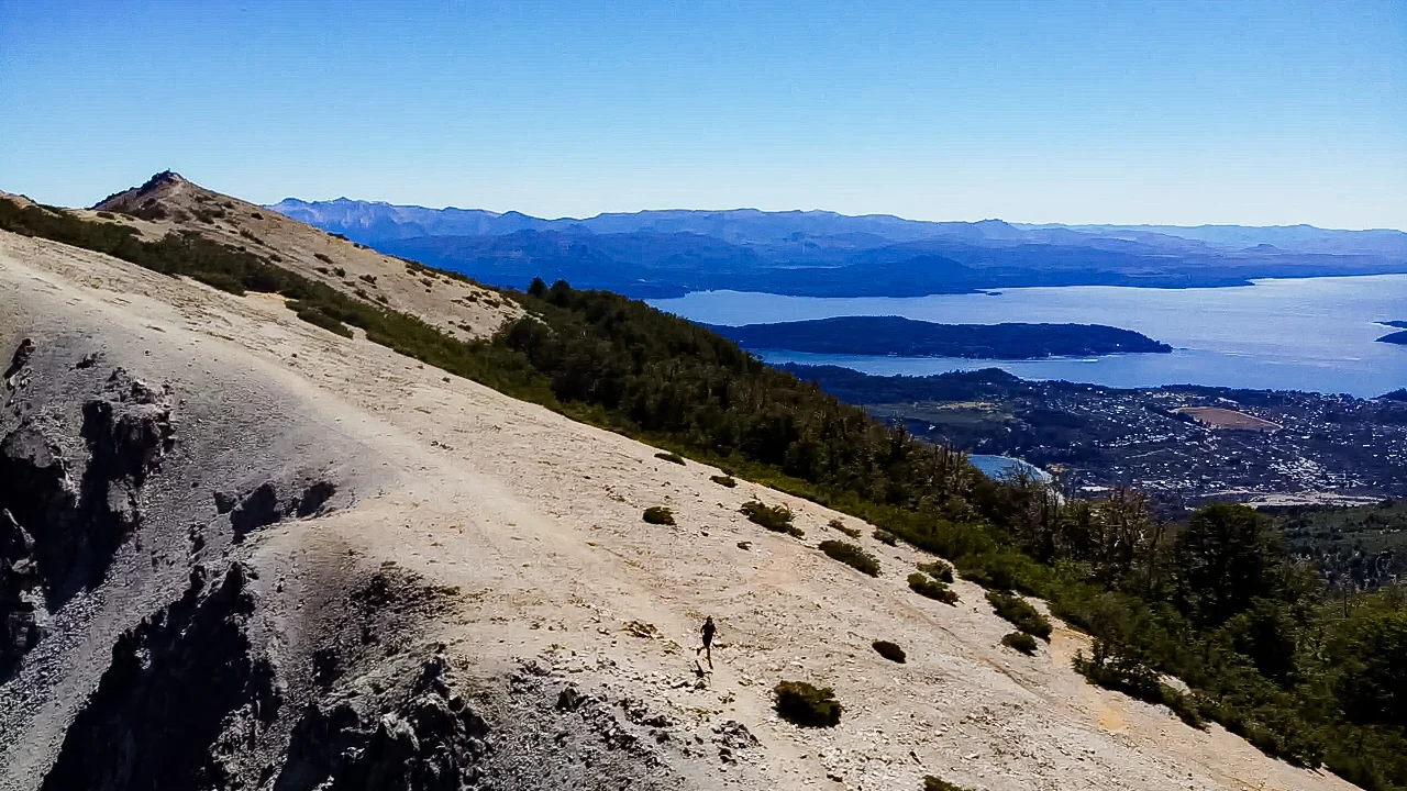 Vista panorâmica de Bariloche e do Lago Nahuel Huapi vista do alto, com encosta de pedra e a cidade ao fundo